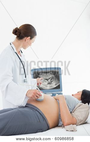 Female doctor performing ultrasound on pregnant woman in hospital