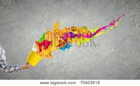 Close up of hand splashing colorful paint from bucket