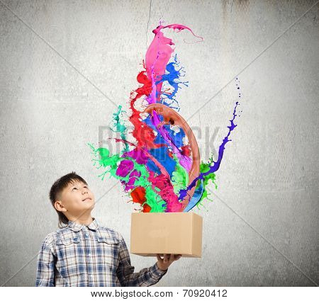 Young boy splashing colorful paint from carton box