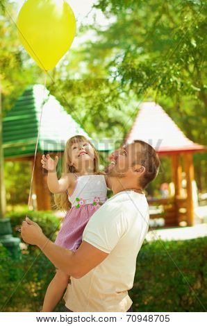 Father and daughter looking at yellow balloon