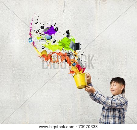 Young boy splashing colorful paint from bucket