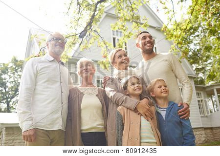 family, happiness, generation, home and people concept - happy family standing in front of house outdoors