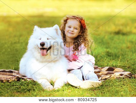 Happy Child And Dog Resting On The Grass In Warm Sunny Day