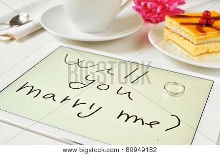 a ring and the sentence will you marry me? written in a tablet on a table at dessert time