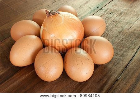 Eggs And Onion On A Brown Wooden Table.