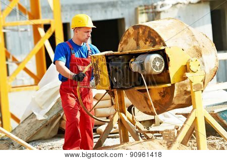 builder man working with shovel during concrete cement solution mortar preparation in mixer at construction site