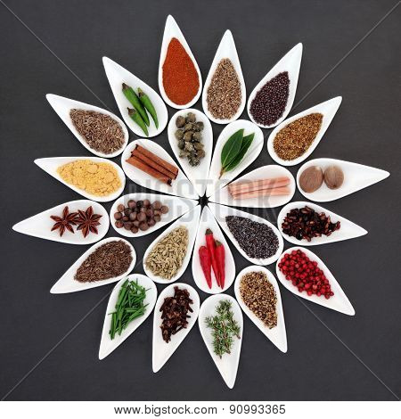 Herb and spice seasoning selection in porcelain bowls over slate background.