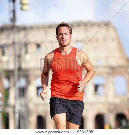 Runner man running at italian city Rome marathon near Colosseum, Roma, Italy. Handsome male athlete training cardio jogging on street with famous touristic attraction landmark in the background.