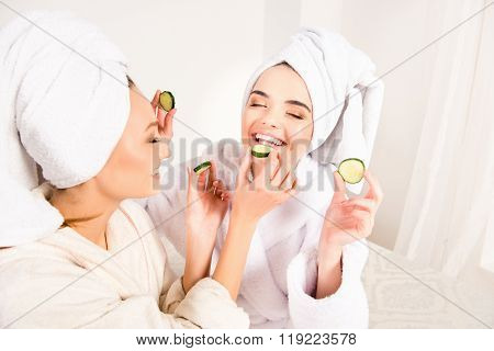 Funny Young Girls With Towels On Their Heads Feeding Ech Other With Slices Of Cucumber
