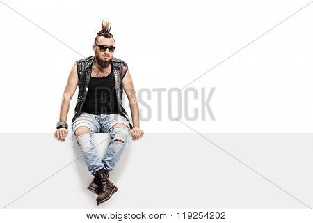 Young punk rocker with a Mohawk hairstyle and a leather vest sitting on a panel isolated on white background
