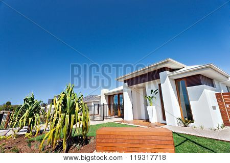 Residential Area With Luxurious Houses And Gardens In The Clear Blue Sky Background