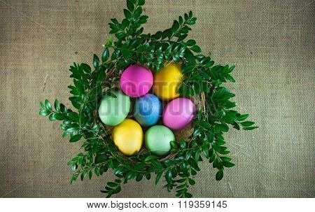 Easter Eggs In The Wicker Basket With Green Branches. Top View
