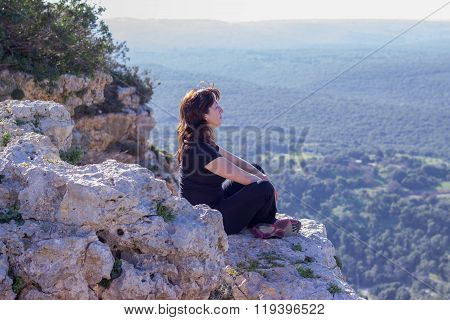 woman in a black tracksuit sitting on the cliff