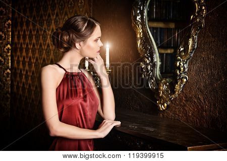 Romantic young woman in evening dress posing in vintage interior. Classic luxurious interior. Fashion shot.