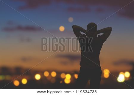 Silhouette of a man with de-focused city lights in the background.