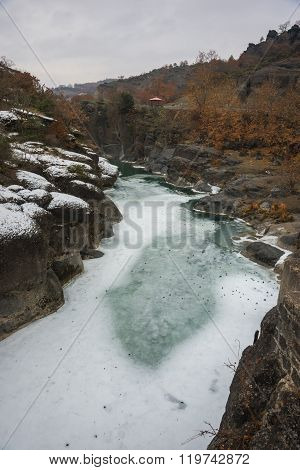 River With Green Waters, Snow And Ice Near Meteora In Greece