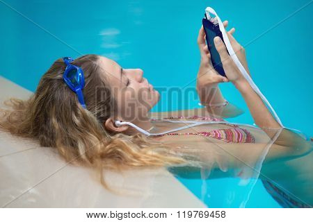 Young female swimer is listening to music 