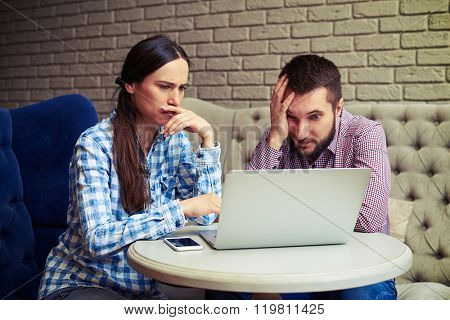portrait of despondent couple looking at laptop