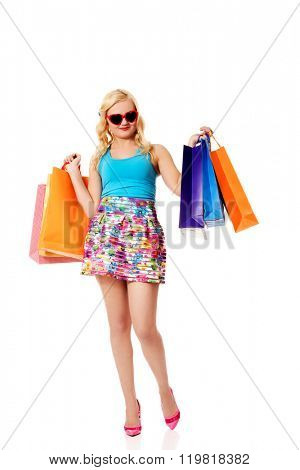 Happy woman in sunglasses holding shopping bags