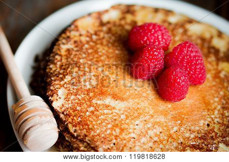 Pancakes With Maple Syrup And Raspberries On Wooden Background