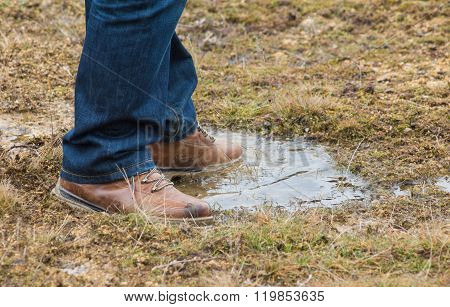 Feet Of A Person Standing In A Puddle Of Water