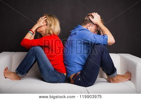 Couple with their backs turned to each other sitting on couch