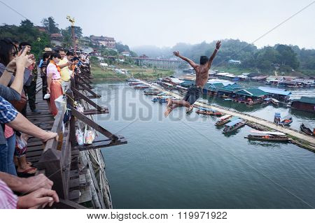 Sangkhlaburi, Thailand - December 27, 2015: Asia Young Boy Jump Into River From Wooden Bridge In Mor