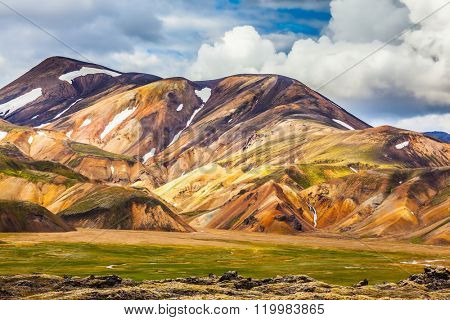  Summer volcanic tundra.  Bright, multi-colored rhyolite mountains - yellow, orange, green and blue. Travel to Iceland in July