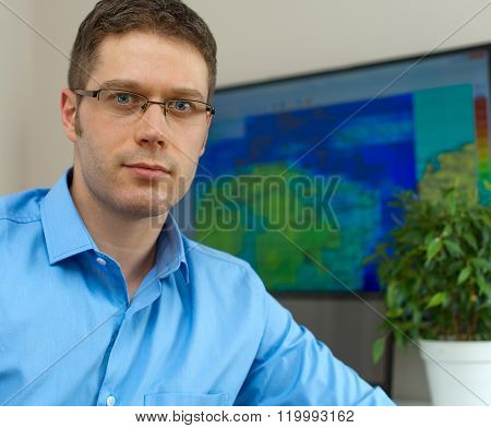 Handsome male meteorologist in glasses on his workplace.