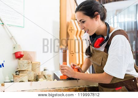 Carpenter woman working with planer in her workshop