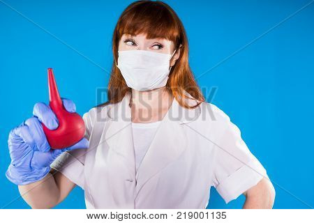 a girl in a dressing gown a nurse in a mask holds an enema in her hand