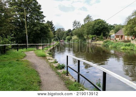 A small canal boat floats off into the distance on the Leeds Liverpool canal near Wigan