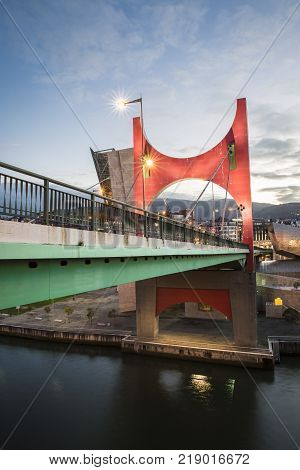 Bilbao, Spain - January 29, 2016: evening view of La Salve Bridge with its Arcos Rojos or Red arches, sculpture designed by French Artist Daniel Buren and inaugurated in 1997