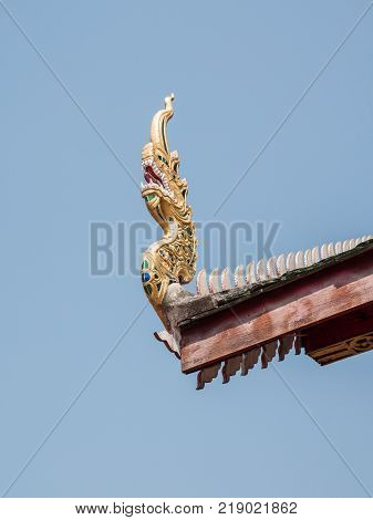 Wooden dragon head from the carving in the traditional northern Thai style on the eaves of the church.