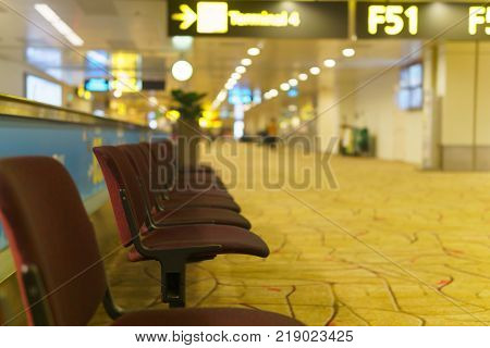 Row of empty brown chair for passenger to wait before departure time in gate F51 at the airport.