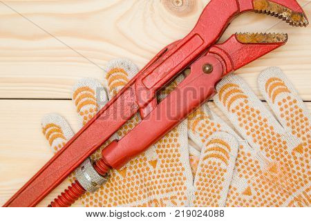Repairing and construction concept. Tools for house repair- pilers and a pair of protective work gloves on a light uncolored wooden background, close up. Top view. Space for your text or pruduct display.