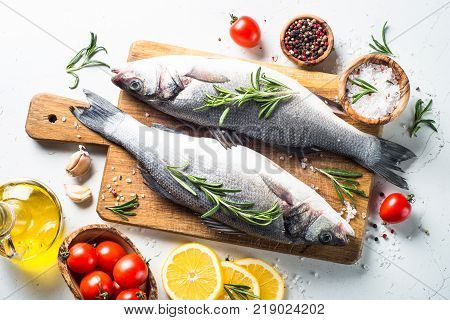 Fresh fish seabass. Raw fish seabass with spices and herbs ingredients for cooking on white background. Top view.