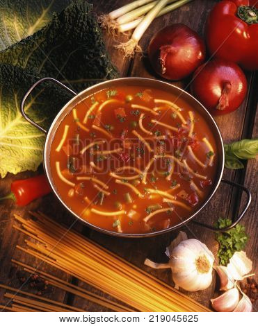BOWL OF TOMATO AND PASTA SOUP WITH RED PEPPERS ONIONS AND SPAGHETTI