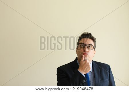 Pensive contemplative businessman rubbing chin and looking up. Thoughtful handsome male manager finding inspiration. Generating idea concept