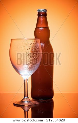 Bottle of beer and glass empty condensate cold refreshing Still life on golden translucent background studio shot