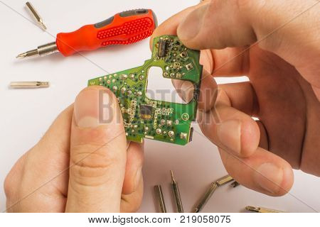board in hands on a white background with a red screwdriver and interchangeable tips with a screwdriver