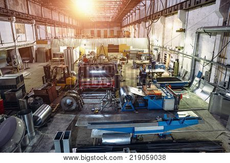 Industrial factory with equipment tools in large workshop or warehouse, manufacturing and steel works, industrial background, sunlight effect