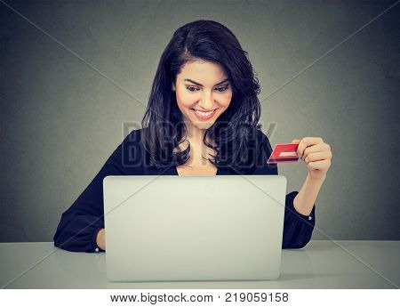 Internet shopping and payment. Smiling young woman holding credit card and using laptop computer