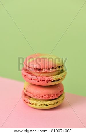 a pile of delicious pink and green macarons of mixed flavors on a pink and green background with a blank space on top