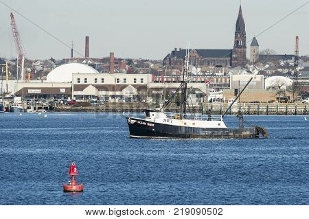 New Bedford Massachusetts USA - November 28 2017: Fishing boat Ocean Wave crossing Acushnet River with New Bedford backdrop