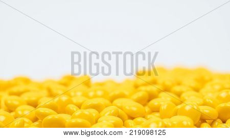 Yellow sugar coated tablets pills on white background with copy space. Medicine for treatment constipation.
