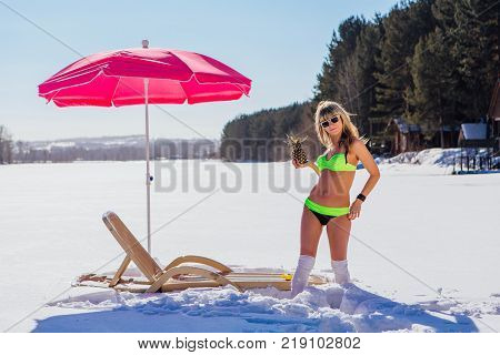 Novokuznetsk, Kemerovo region, Russia - 23 Feb, 2017 : White beaches of Siberia is an enterteiment activity where people playing beach games dressed in bikini in winter. Woman in bikini with pineapple