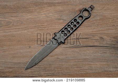 Steel butterfly knife (balisong) isolated on a wooden background