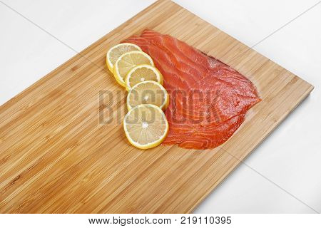 Smoked Fillet trout with lemon on a cutting board. Seafood.