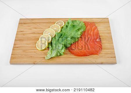 Smoked Fillet salmon with lemon and salad on a board